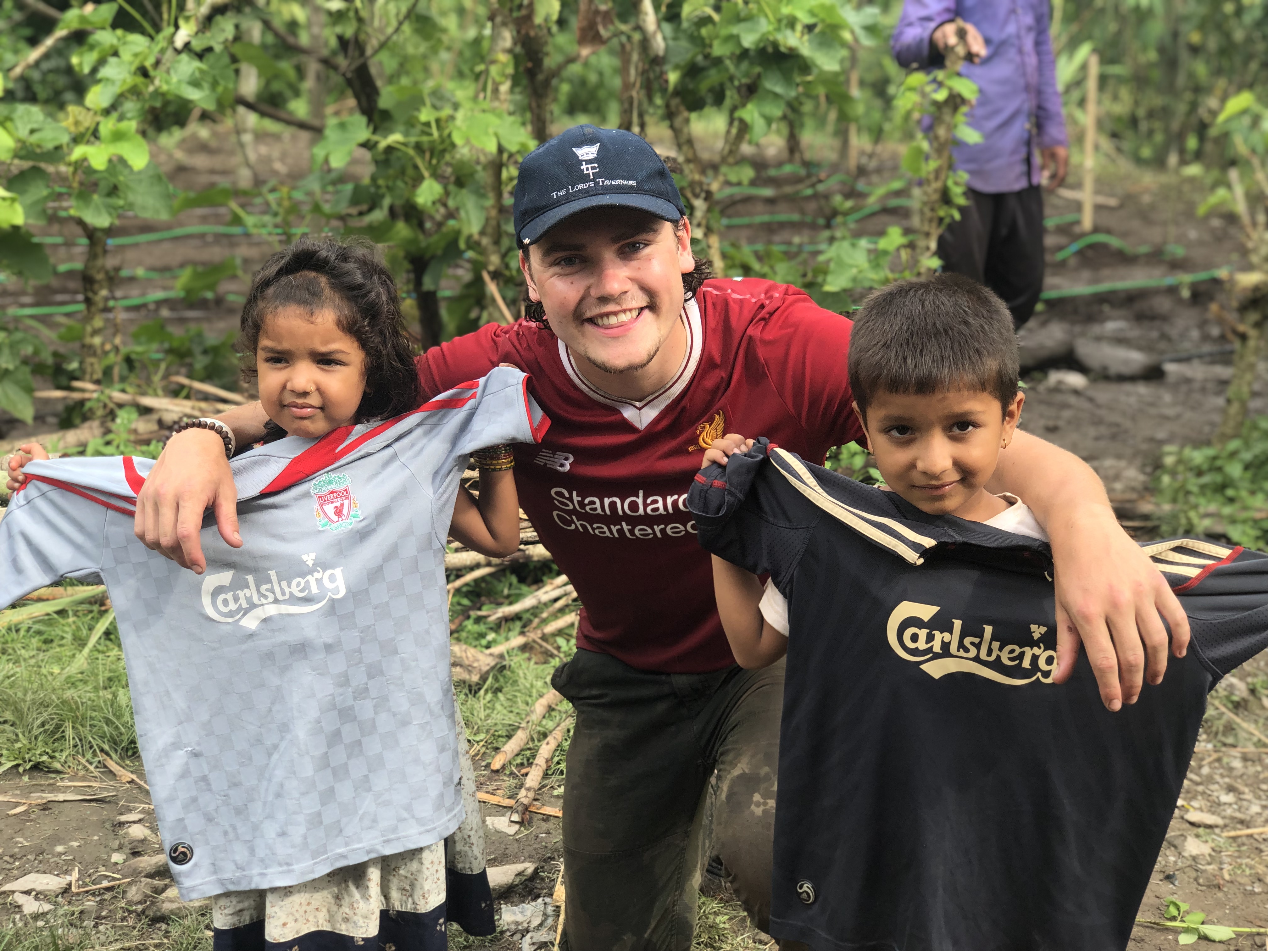 Sam with two local children, handing over football shirts