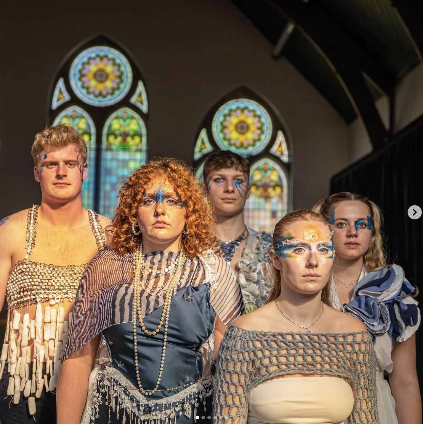 Five models in upcycled garments against stained glass windows
